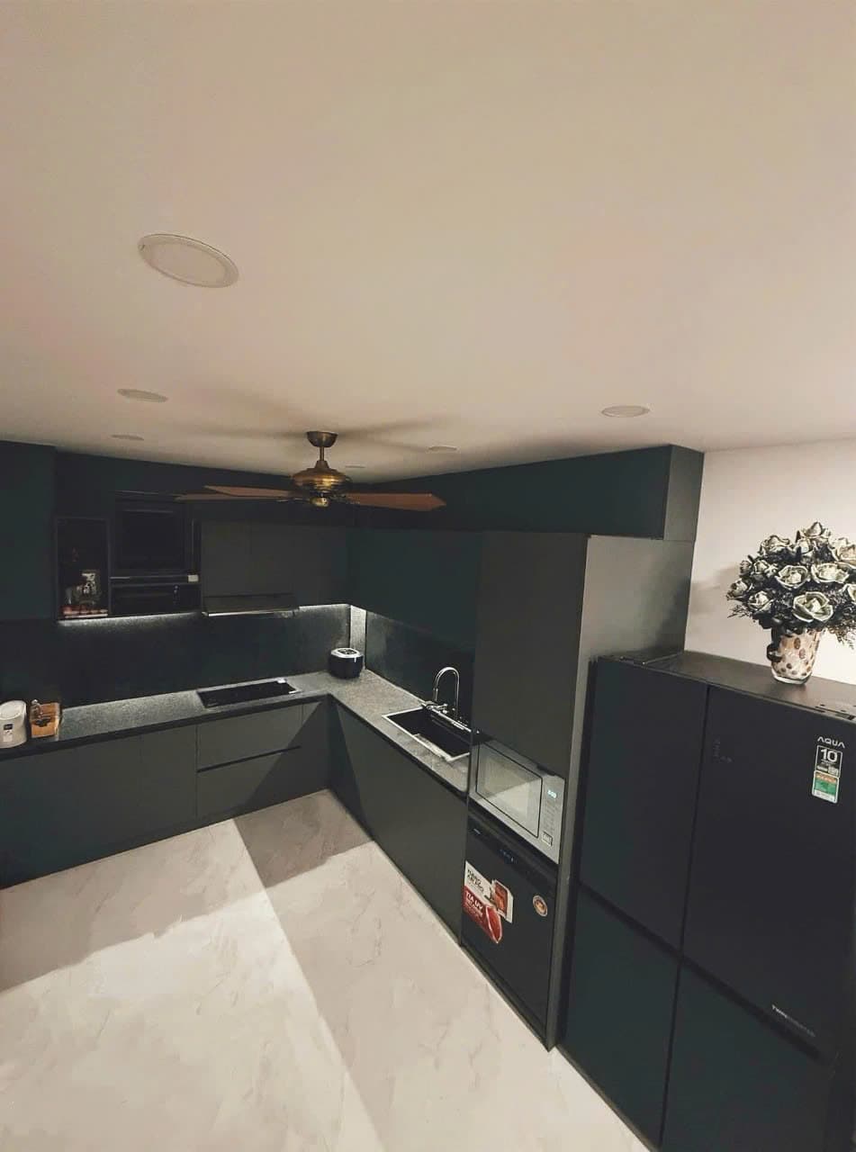 Tủ bếp chữ L phối trắng xám với mặt đá tối màu trong không gian nhà ở thực tế