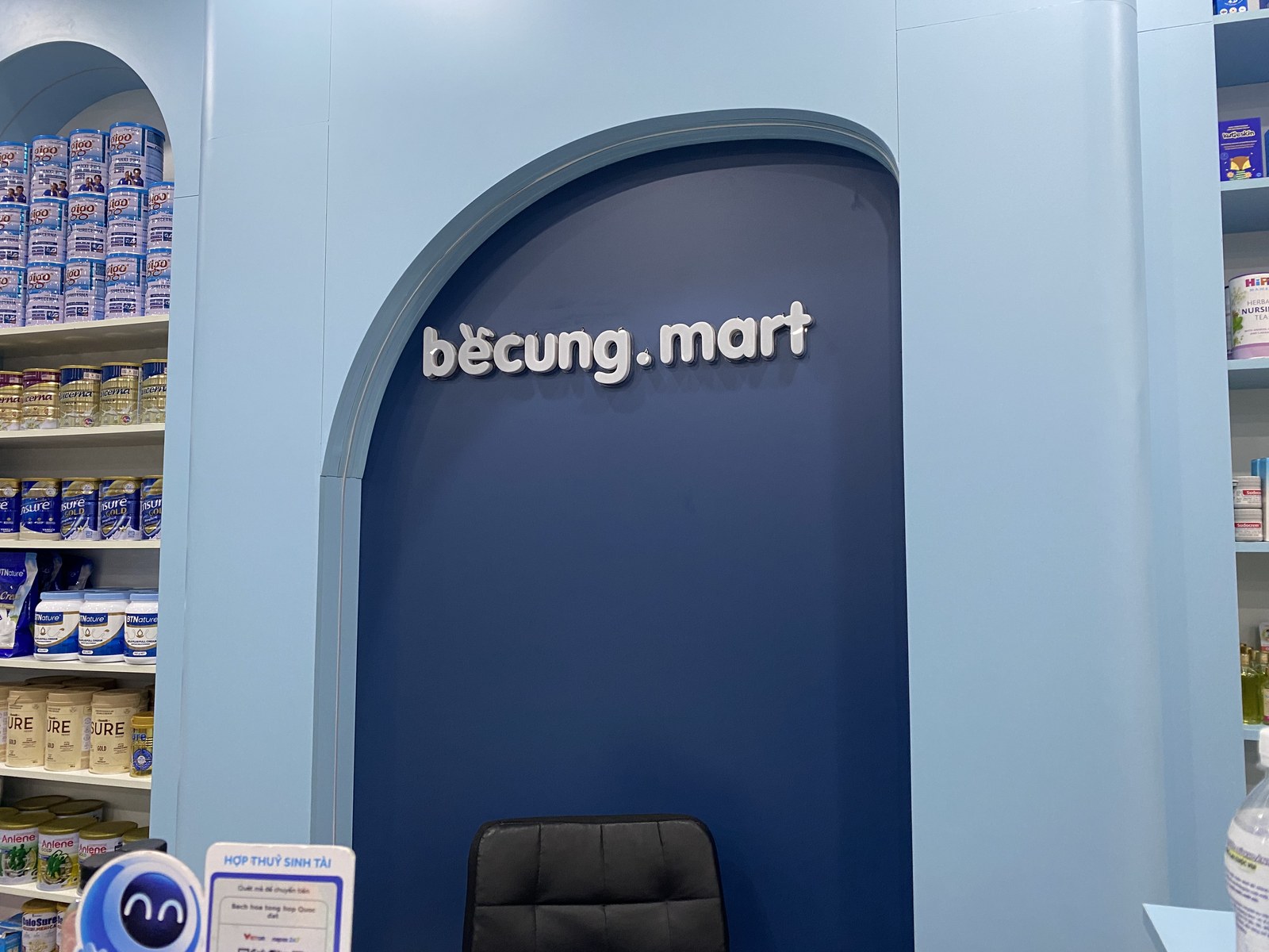 Quầy thu ngân với logo bé cưng.mart và mảng vòm xanh nhận diện thương hiệu